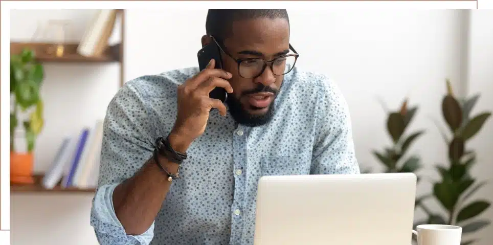 A man reviews his long-term disability information on a laptop while on the phone with a long-term disability lawyer