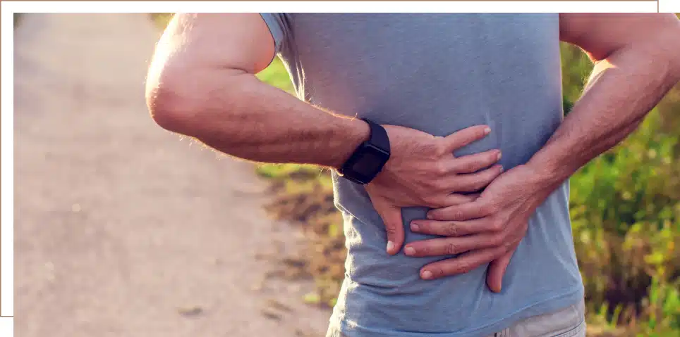 A man clutches his back in pain while out for a walk.