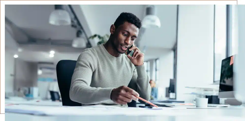 A man reviewing paperwork while on the phone