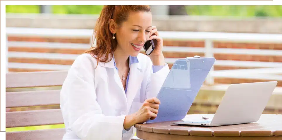 A woman on the phone smiling and looking at a patient's chart